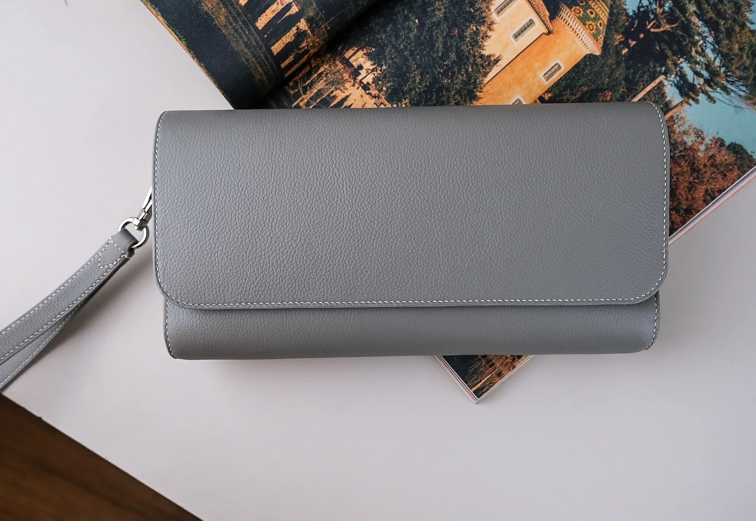 Ảnh Lifestyle Ví clutch da Togo màu xám nắp gập kèm quai cổ tay - Koi Leather