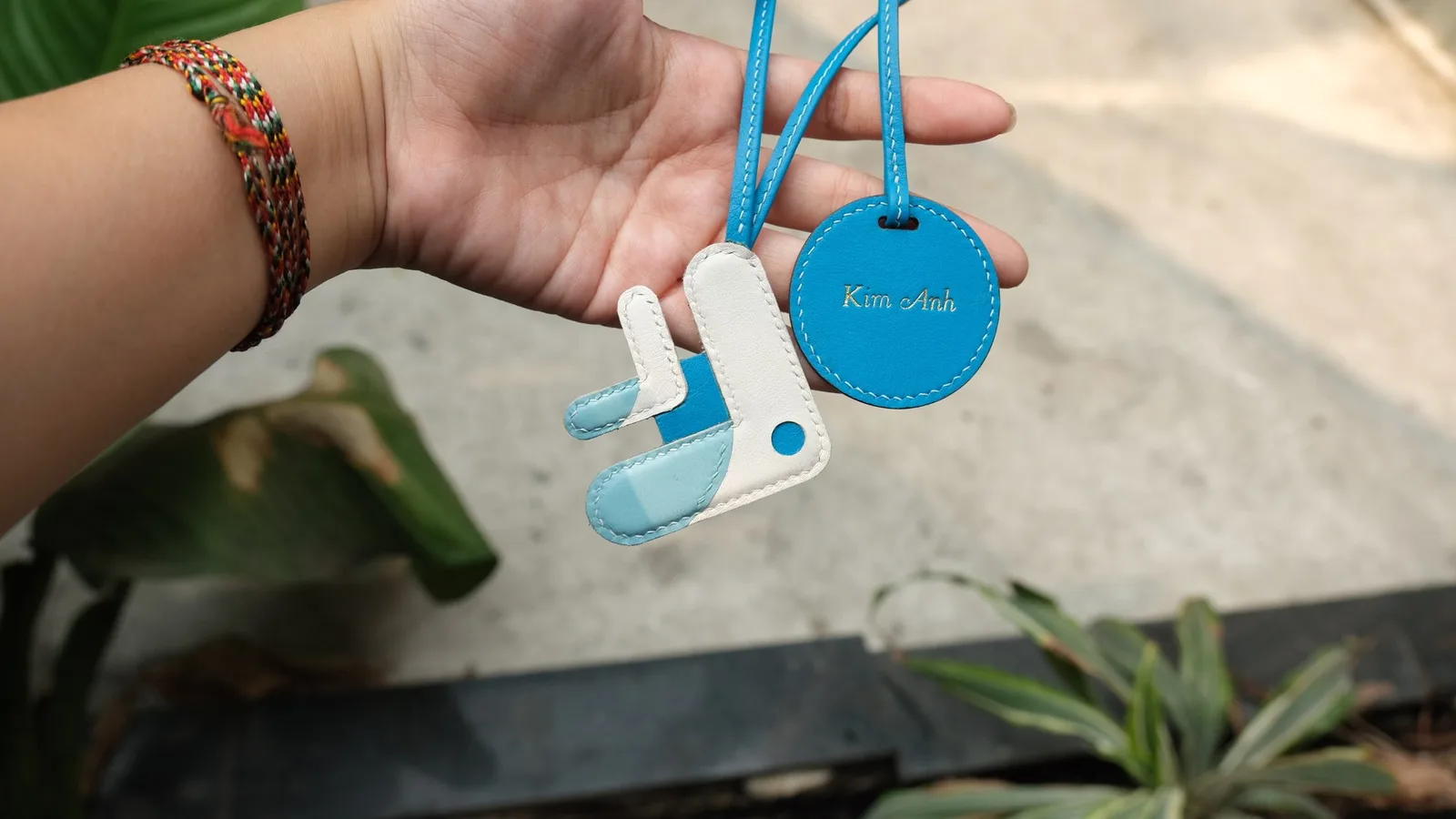 Ảnh Lifestyle Charm đeo túi da phối màu hình cá kèm tag tròn - Koi Leather