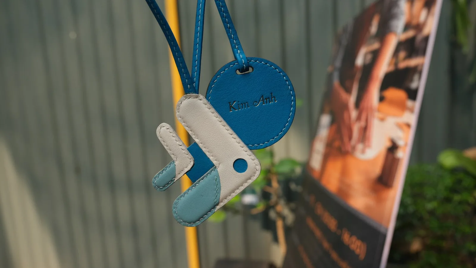 Ảnh Lifestyle Charm đeo túi da phối màu hình cá kèm tag tròn - Koi Leather