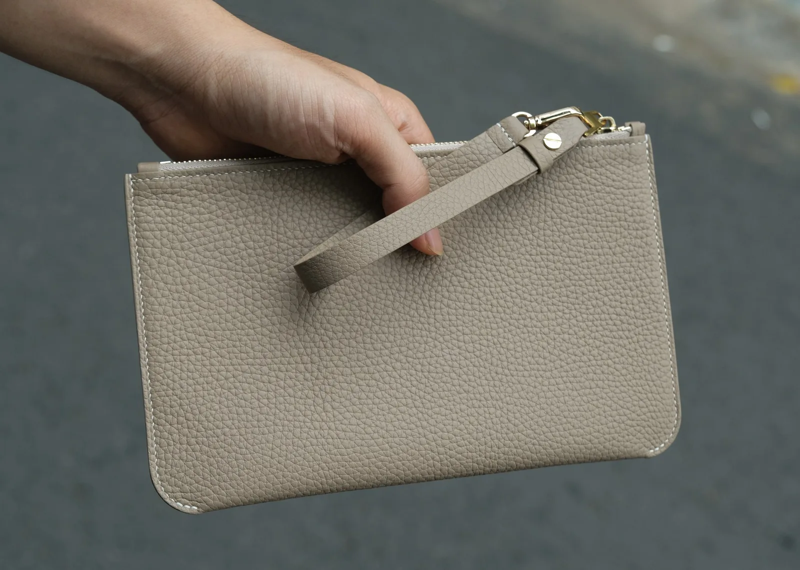 Ảnh Lifestyle Ví clutch da Togo màu kem dáng phẳng có quai đeo - Koi Leather