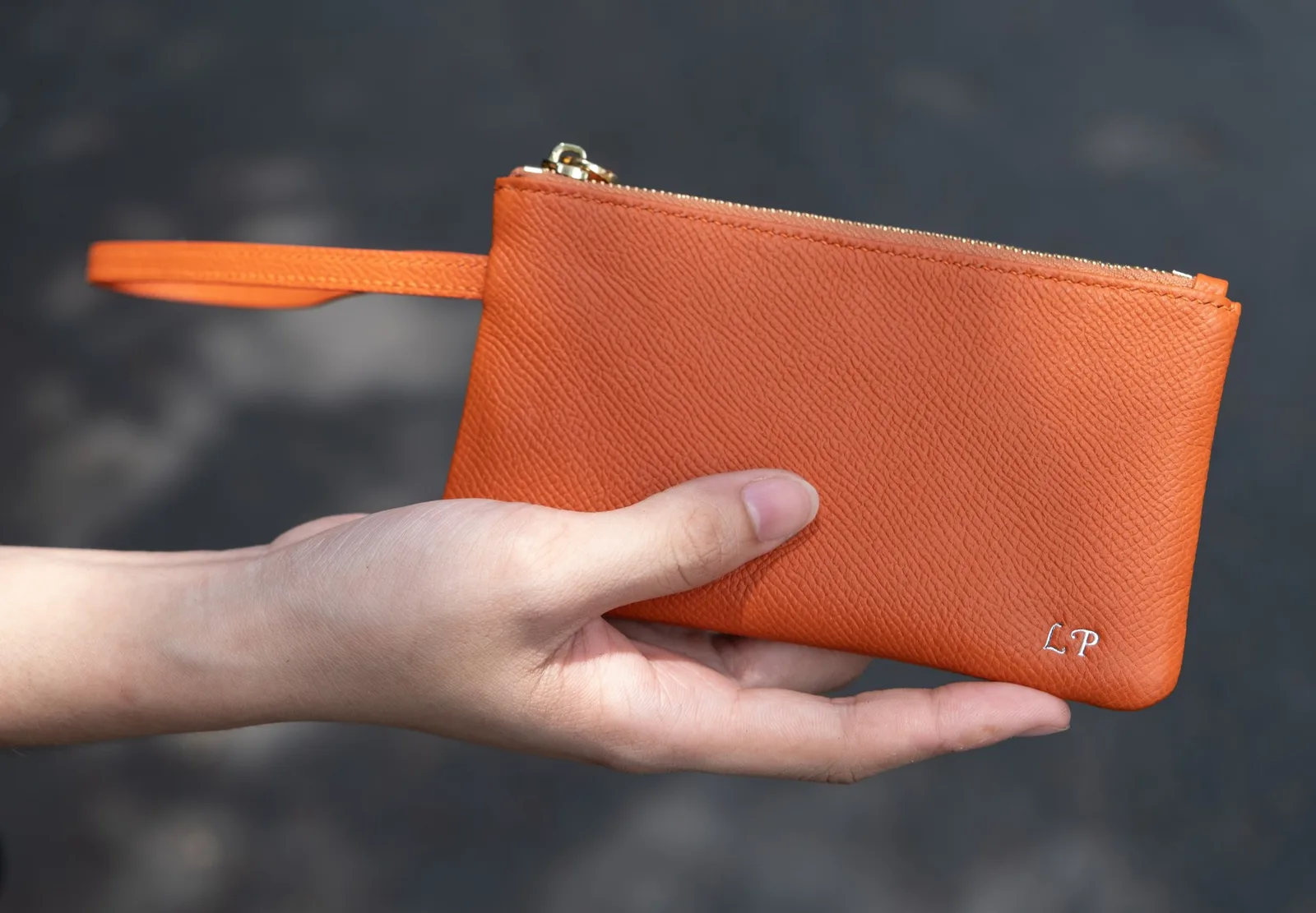 Ảnh Lifestyle Ví cầm tay da Epsom màu cam có quai đeo cổ tay - Koi Leather