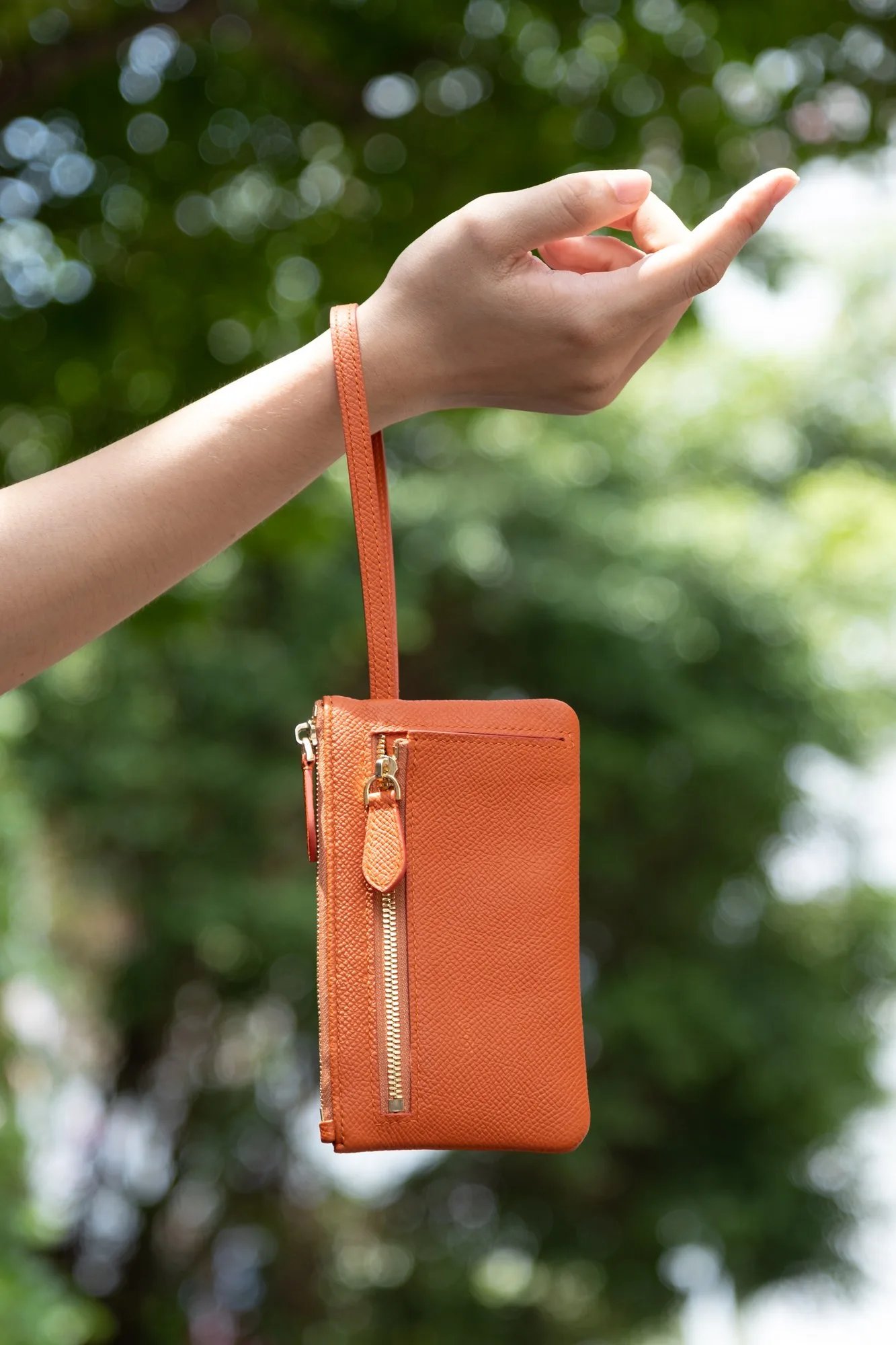 Ảnh Lifestyle Ví cầm tay da Epsom màu cam có quai đeo cổ tay - Koi Leather