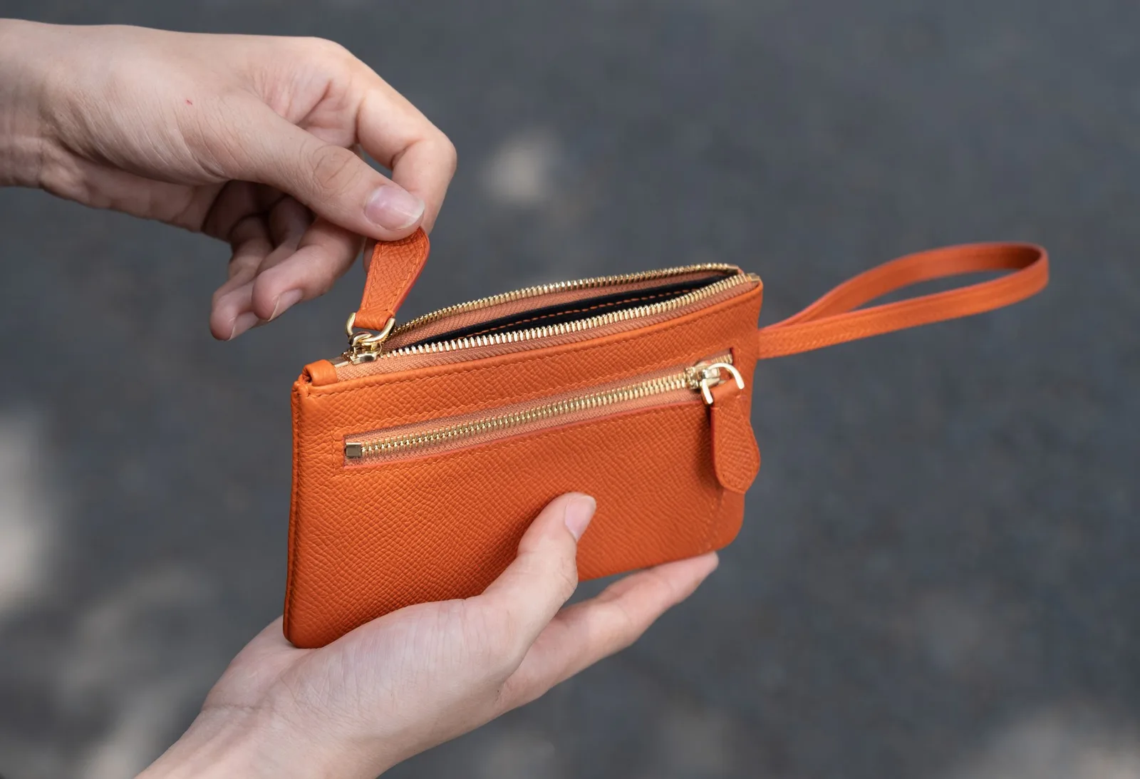 Ảnh Lifestyle Ví cầm tay da Epsom màu cam có quai đeo cổ tay - Koi Leather