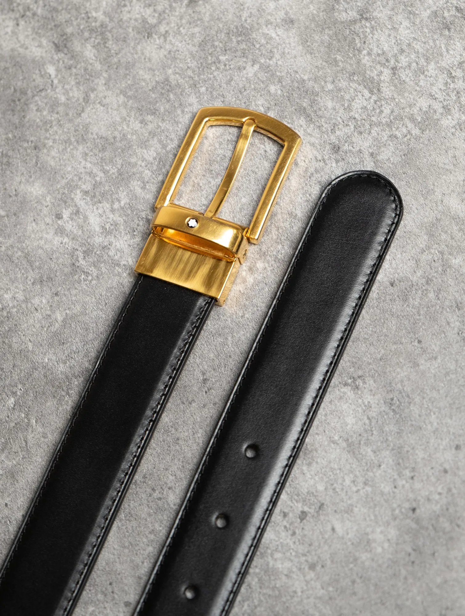 Cận cảnh đầu khóa xoay Montblanc màu vàng lắp vào dây da màu đen may chỉ viền.