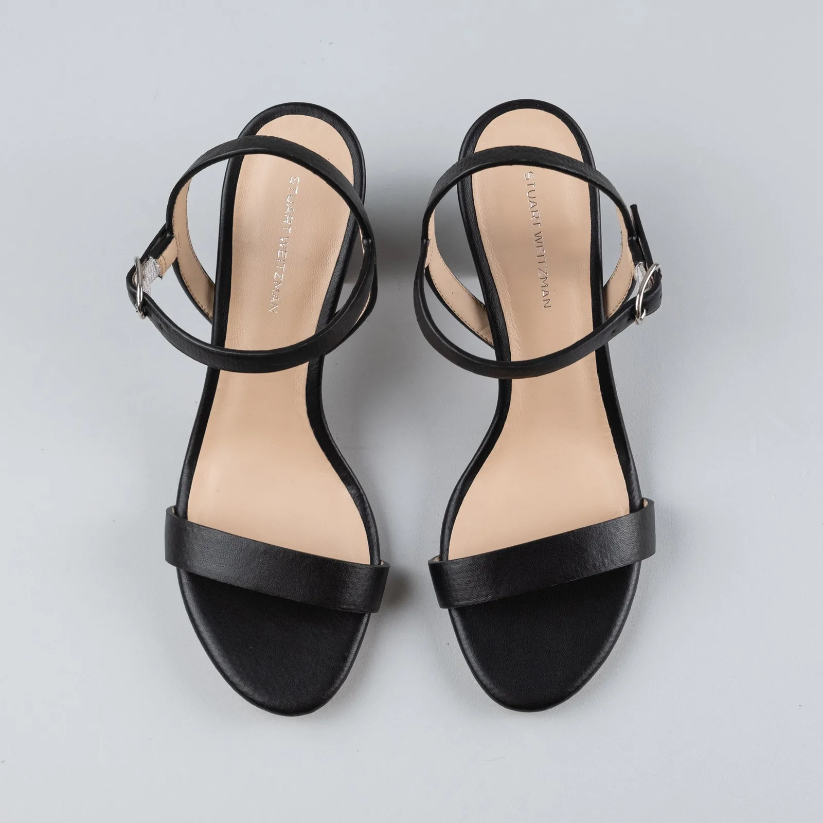 Mặt trên đôi sandal cao gót Stuart Weitzman với lót đế sạch sẽ và quai da đen đều màu