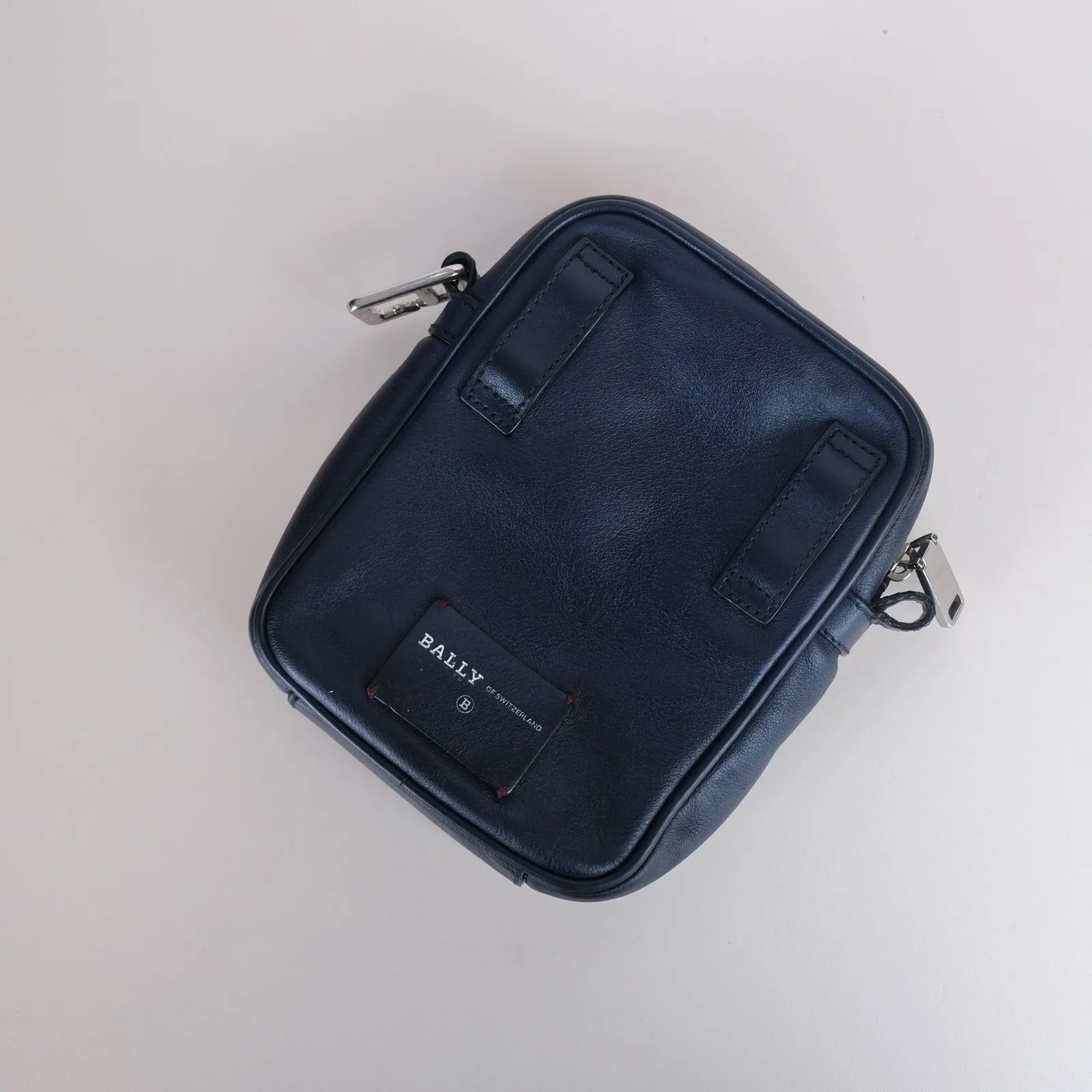 Mặt sau túi đeo chéo Bally màu navy với hai đai gài và mác da