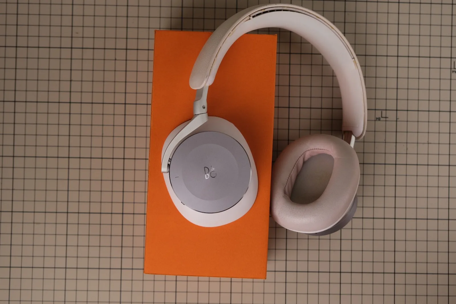 Tai nghe Bang & Olufsen đặt trên hộp cam lộ rõ logo B&O ở ốp tai