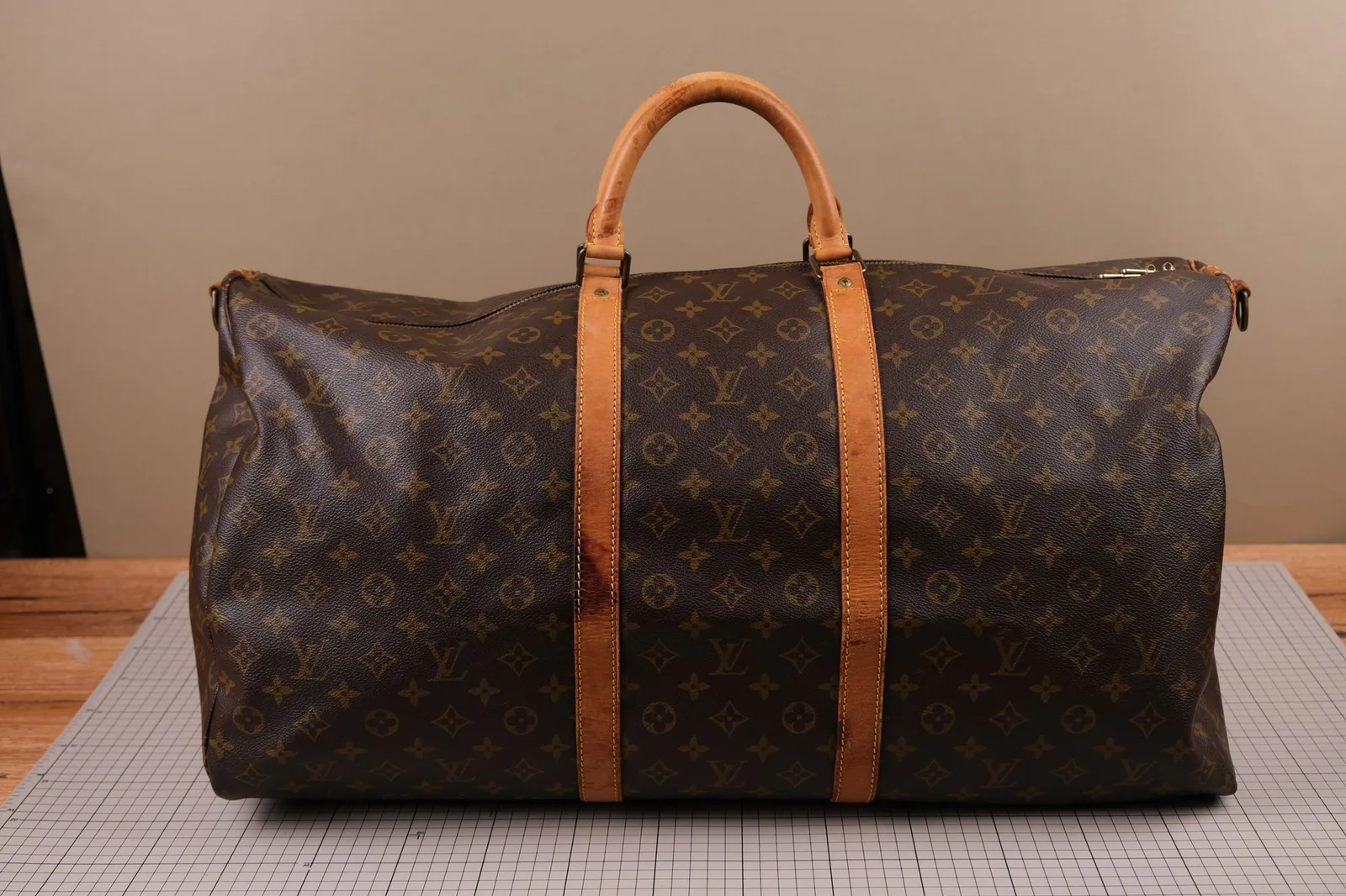 Toàn cảnh túi duffle Louis Vuitton Keepall Monogram với quai và nẹp da vachetta bị ố màu