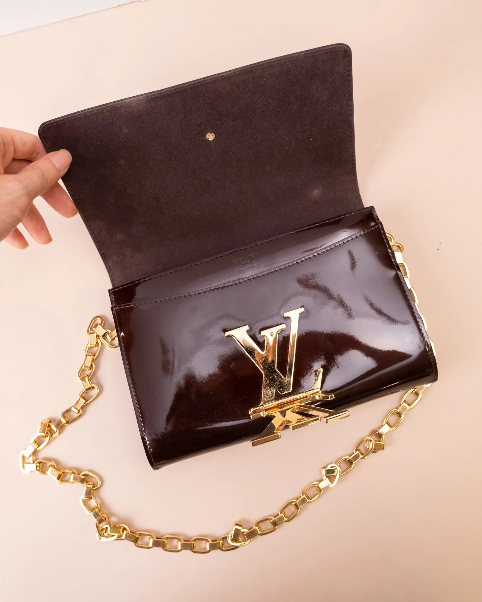 Bên trong clutch Louis Vuitton Louise mở nắp, thấy lớp lót da lộn và dây xích kim loại